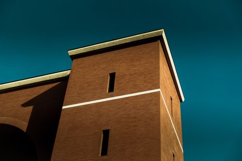 Free Low-angle view of a modern brick building under a vivid blue sky, showcasing contemporary architecture. Stock Photo