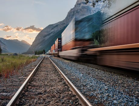Vivid image of a freight train on tracks beneath majestic mountains in Field, BC.