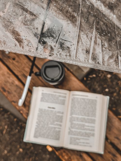 Free Top view of an open book and coffee cup on wooden surface, with raindrops on umbrella. Stock Photo