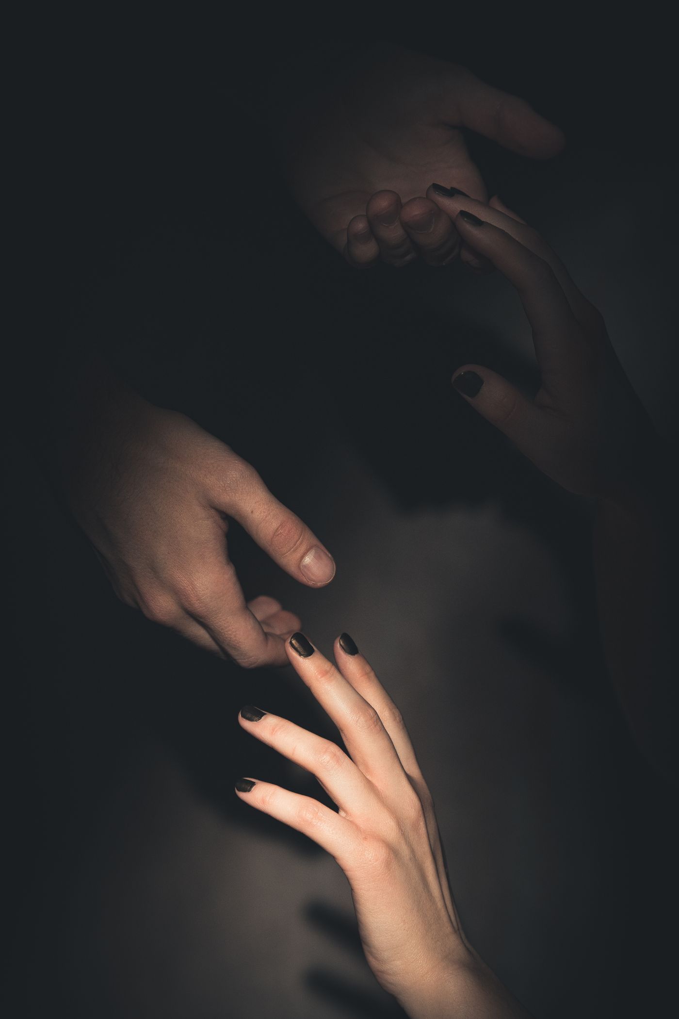 Mãos se aproximando em luz baixa, como imagem conceitual de comunicação e consentimento.
