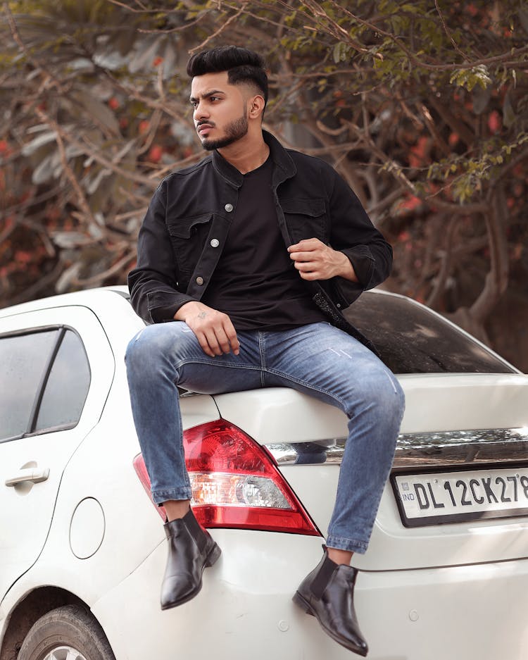 Photo Of A Young Man Sitting On The Trunk Of A White Car