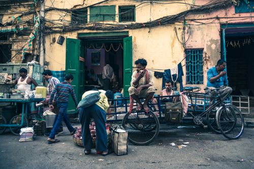 Free Lively street scene in Kolkata featuring men with freight tricycles, vendors, and urban life. Stock Photo