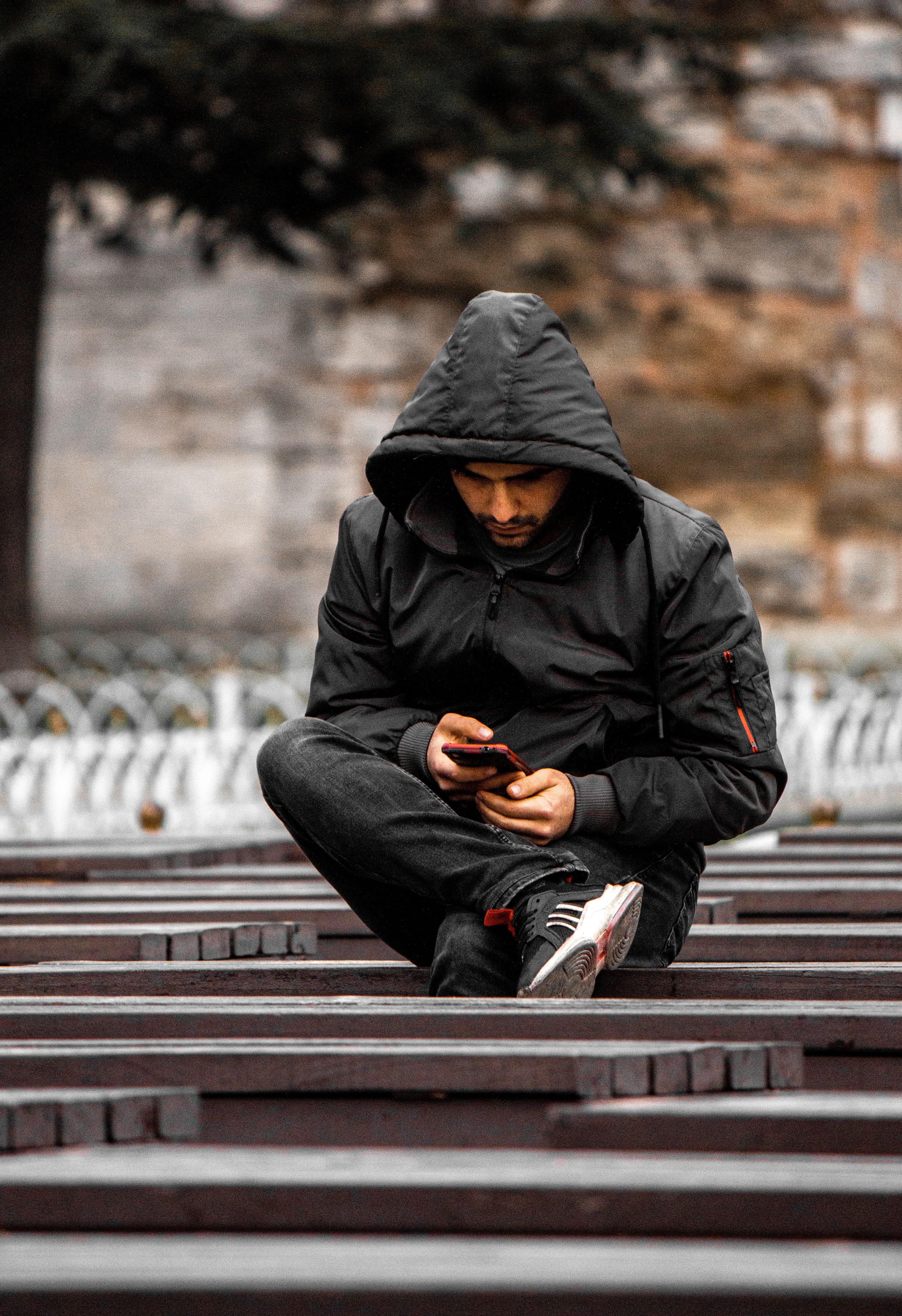 Man Sitting on a Wooden Bench and Using a Smart Phone · Free Stock Photo