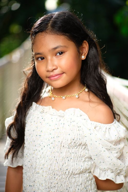 Free A delightful portrait of a smiling girl in a white top and jewelry, captured outdoors in the Philippines. Stock Photo