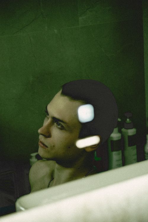 Free Reflective portrait of a young man with moody green tones, focusing on introspection. Stock Photo