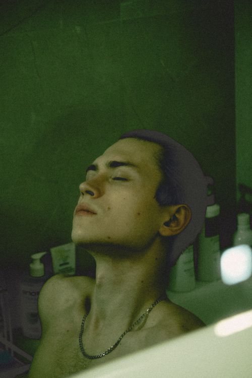Free Young man with closed eyes relaxing in a bathroom setting, conveying a peaceful mood. Stock Photo