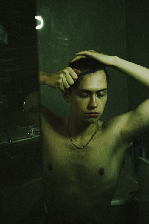 Free A contemplative portrait of a man combing his hair in a dimly lit setting. Stock Photo
