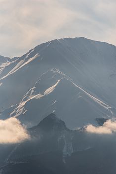 Breathtaking view of snow-covered mountain peaks with clouds in a winter landscape.