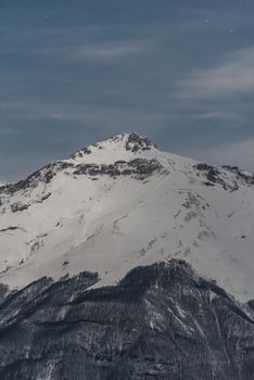 Majestic snow-covered mountain under blue sky showcasing serene winter scenery.