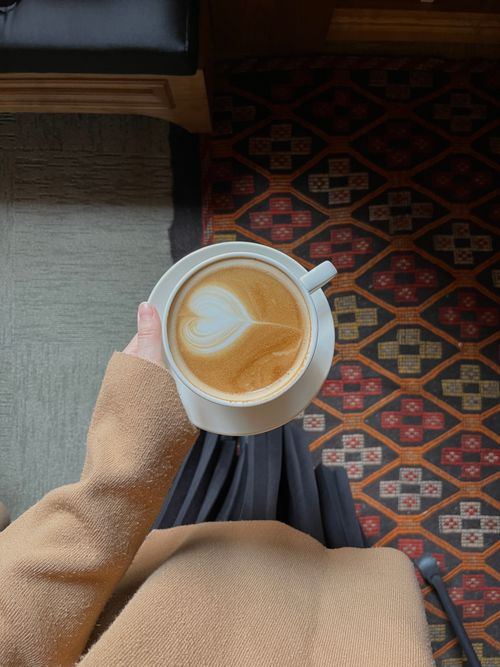 Free A cozy top view of a latte with heart froth art, held by a person indoors. Stock Photo