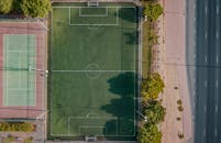 从空中拍摄的迪拜足球场和网球场，四周绿树环绕