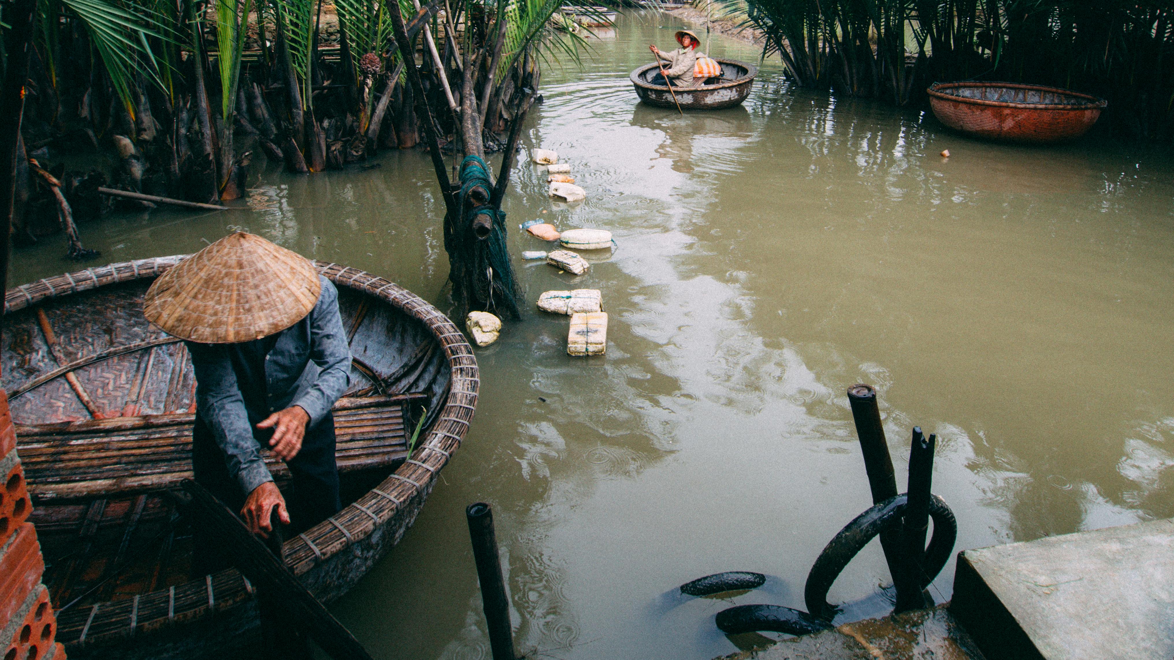 Men rowing traditional basket boats in rural Vietnam's lush waterways. - Nha Trang