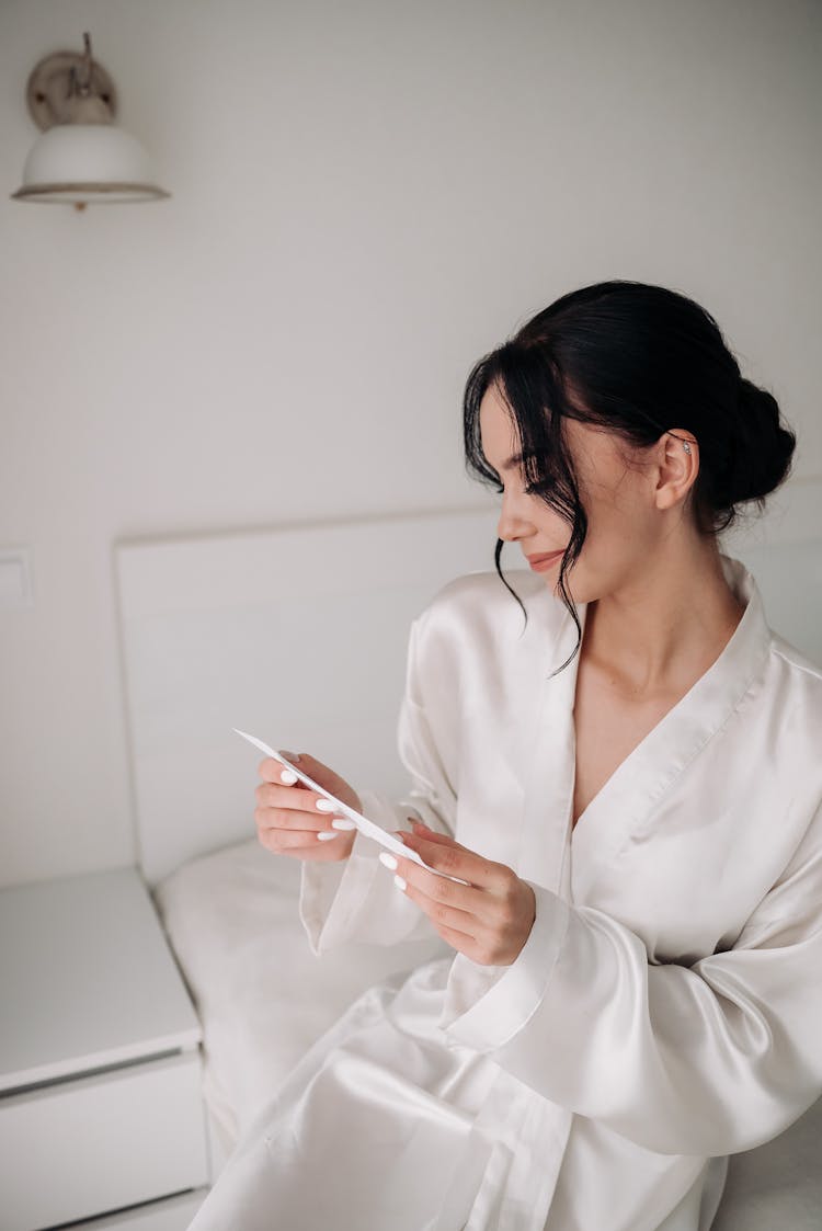 A Brunette Woman In Bathrobe Reading An Invitation