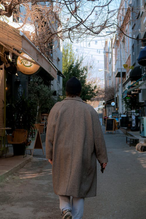 Back of a Person Wearing an Overcoat Walking along a City Alley