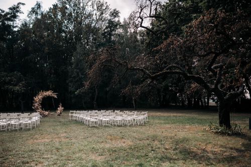 Free Serene outdoor wedding setup with chairs and rustic archway in a lush garden. Stock Photo