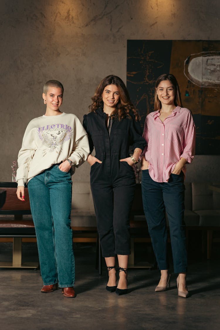 Group Of Young Women In Fashionable Outfits Standing Next To Each Other And Smiling 