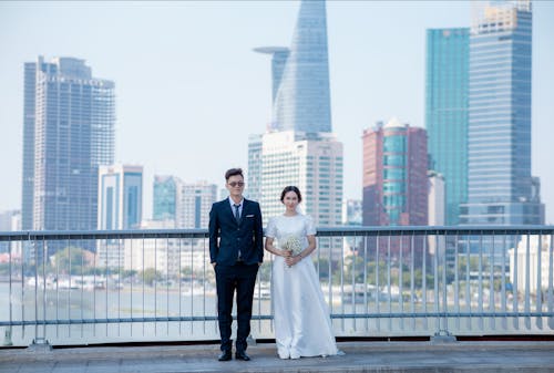 Newlyweds Posing on a Bridge against the City Skyline