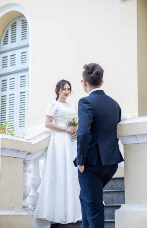 Free Bride and groom posing on a classic staircase, capturing a romantic wedding moment. Stock Photo