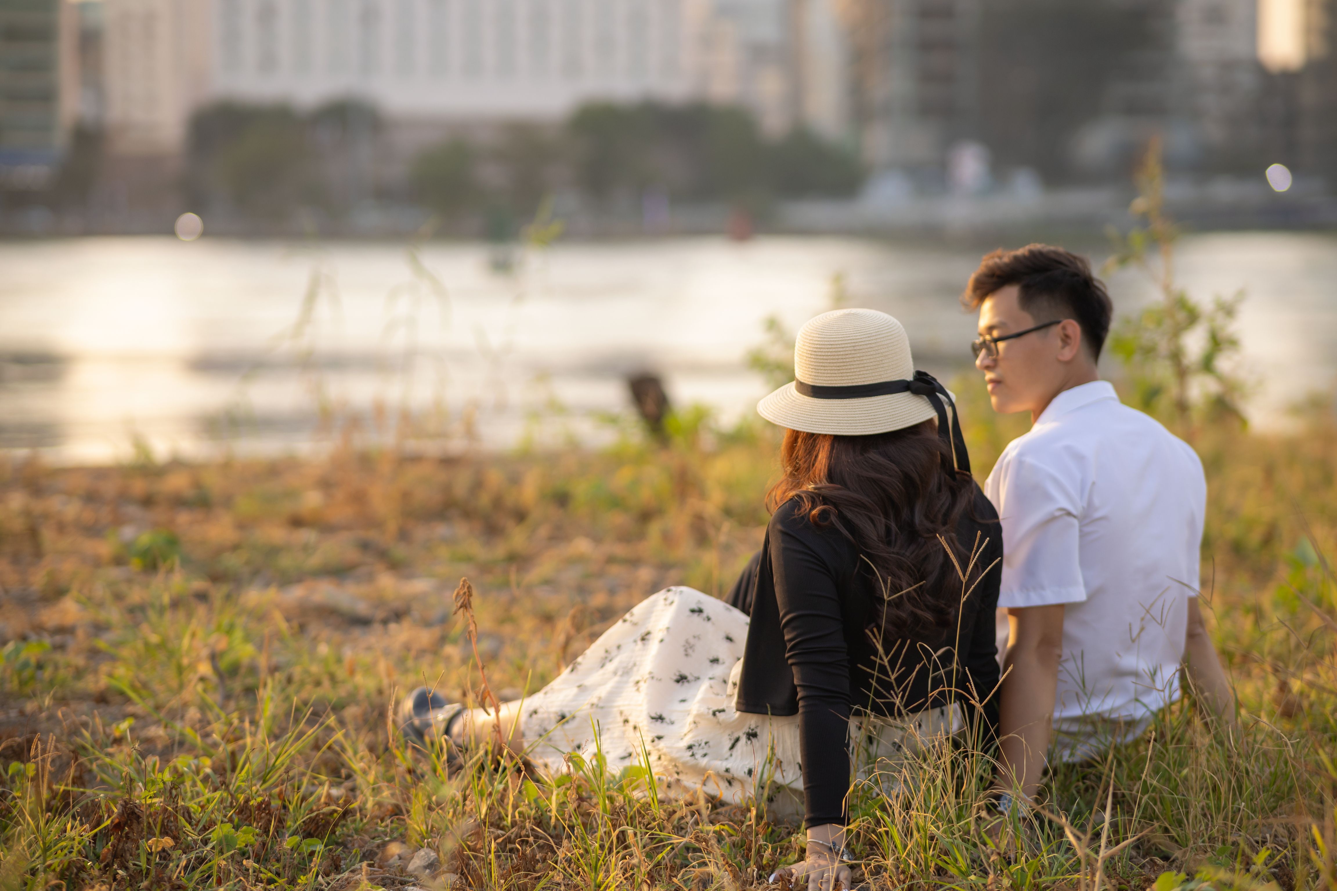 A couple enjoys a tranquil moment by the riverside during sunset, capturing the essence of relaxation and togetherness.