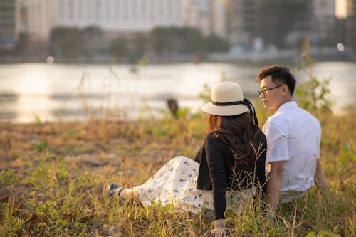 Young Couple Sitting Together on the Grass at Dusk