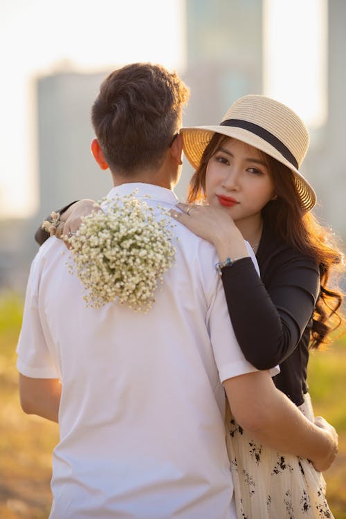 A Couple Hugging Outdoors and Woman Holding a Bouquet of Babys Breath Flowers