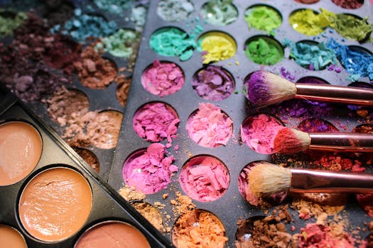A messy, colorful makeup palette with various pigments and brushes in close-up view, creating an artistic display.