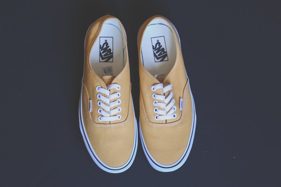 Pair of stylish yellow sneakers on a black background showcasing fashion and footwear design.