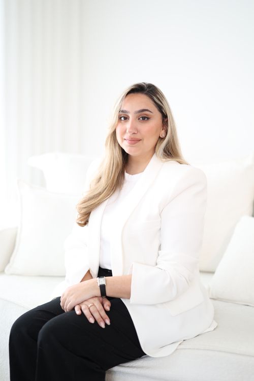 Free Young professional woman in a modern white suit sitting confidently. Chic and sophisticated style. Stock Photo