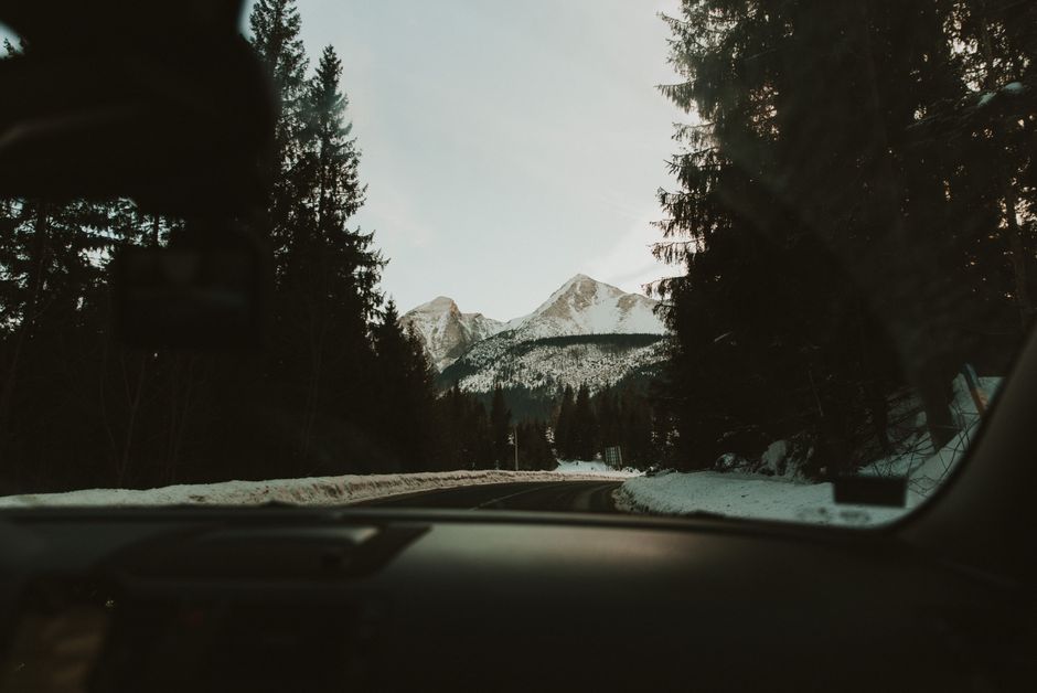 View from a car driving through snowy mountain landscape in winter.