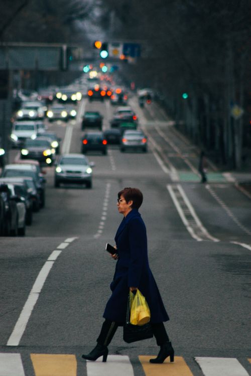Free A woman in a blue coat crossing a busy street in Almaty, Kazakhstan's urban scene. Stock Photo