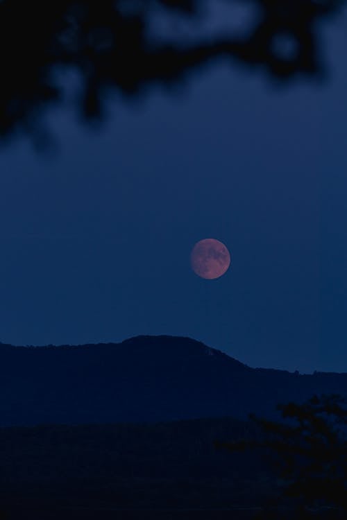 A Red Full Moon over a Mountain at Night 