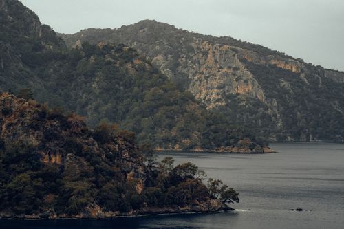Free A tranquil view of an island surrounded by lush green mountains and a serene sea. Stock Photo