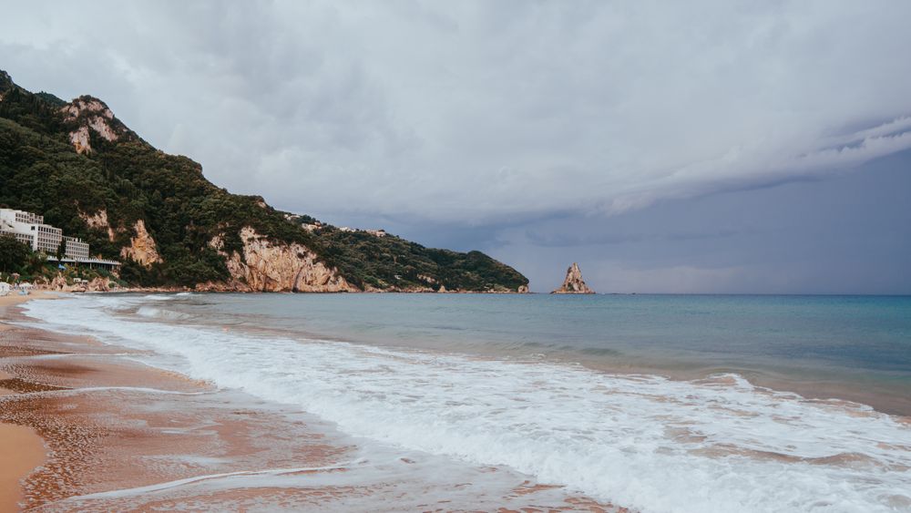 Plajă din Corfu cu nisip auriu, apă turcoaz și faleze verzi
