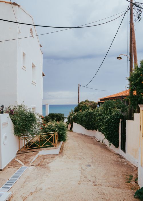 Free Quaint pathway in a coastal village leading to the sea, surrounded by charming houses. Stock Photo
