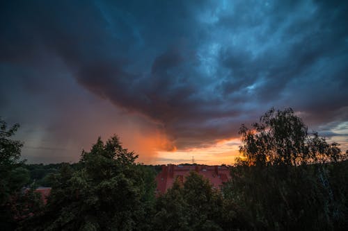 View of Trees and Rooftops under a Dramatic Sunset Sky 