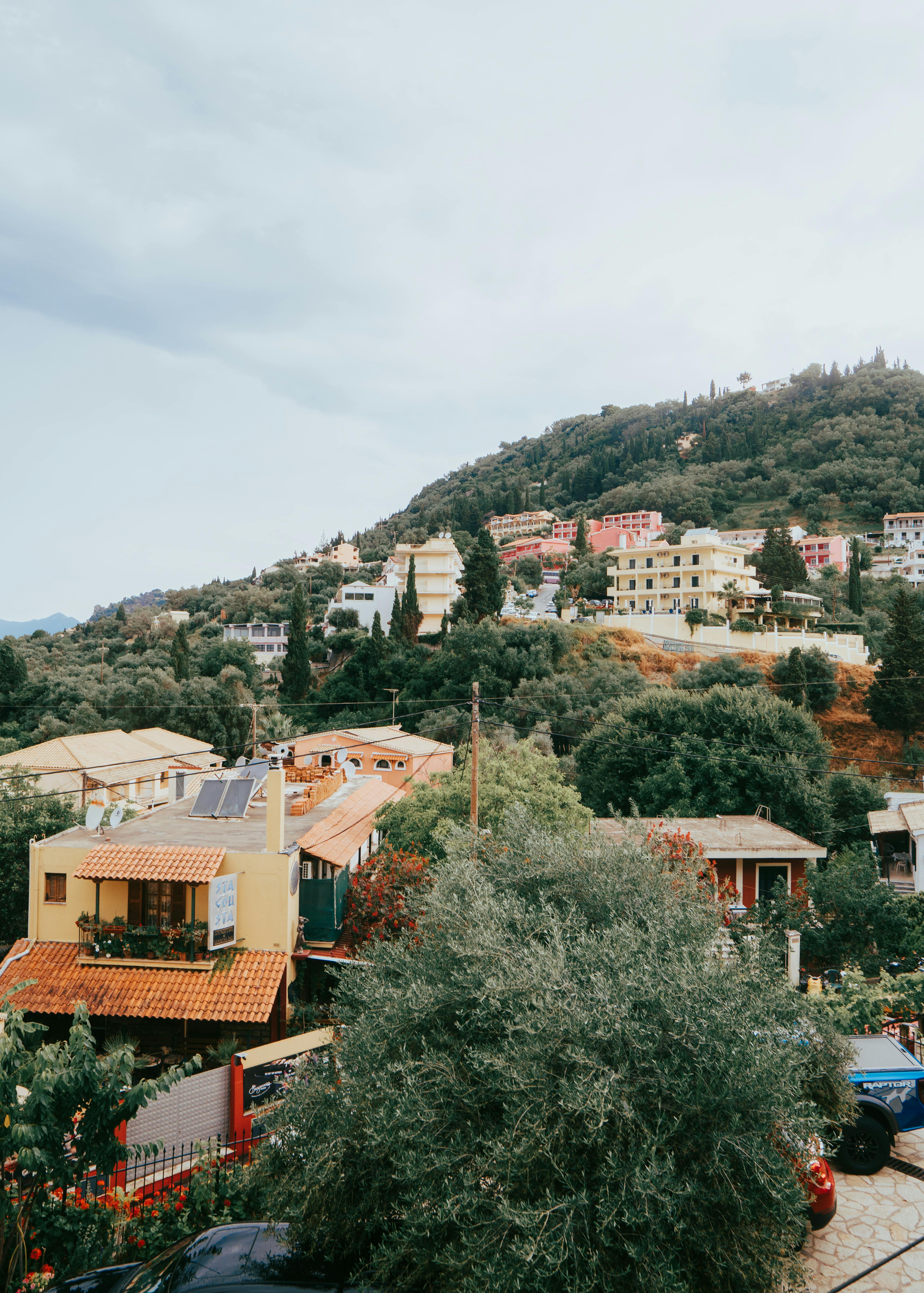 Scenic view of a Mediterranean hillside town with colorful buildings and lush greenery.