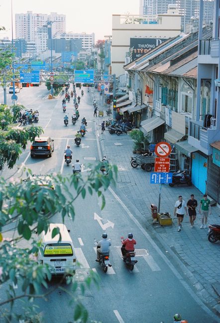 High angle view of busy street in Vietnam with motorbikes and cars, capturing urban lifestyle and architecture.