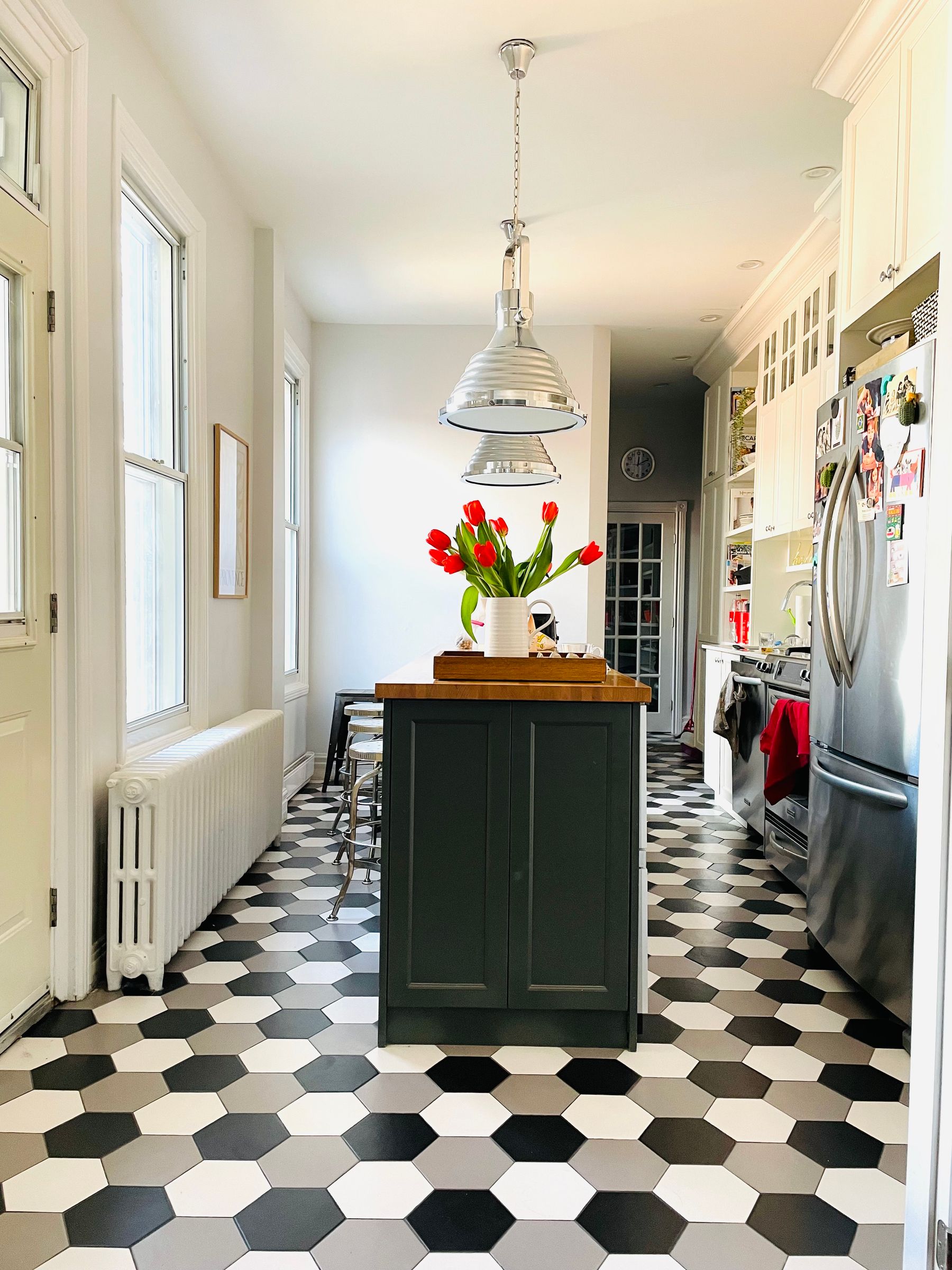 Bright modern kitchen with bold black-and-white checkerboard flooring and a flower vase on the counter