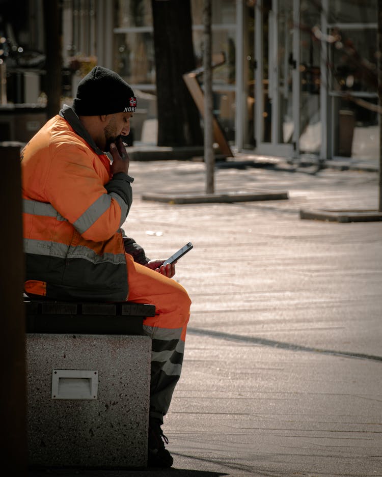 A Man In Reflective Clothing Looking At Smartphone