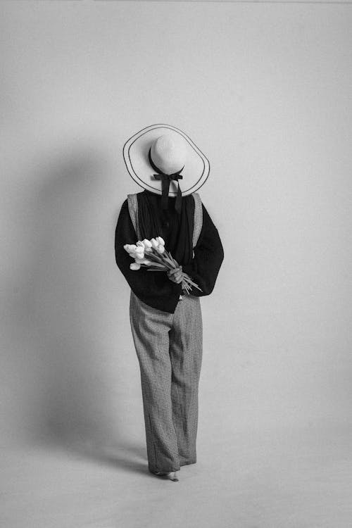 A woman in a hat and suit holding flowers