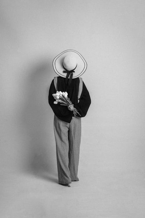 A person in a hat and suit holding flowers