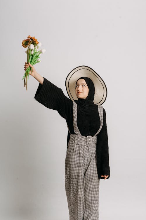 A woman in a hijab holding a flower