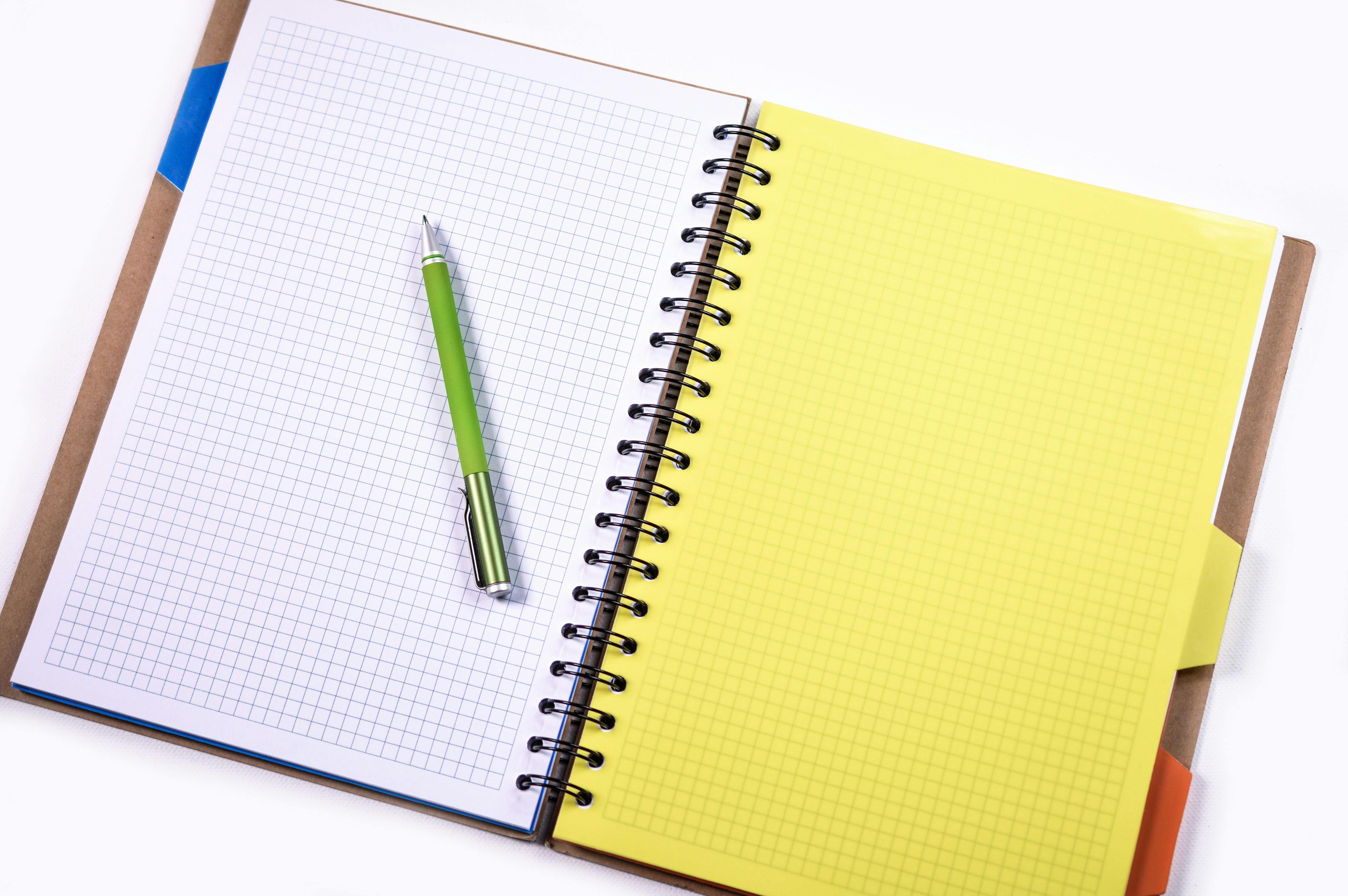 Green Click Pen On A White Graphing Notebook Free Stock Photo