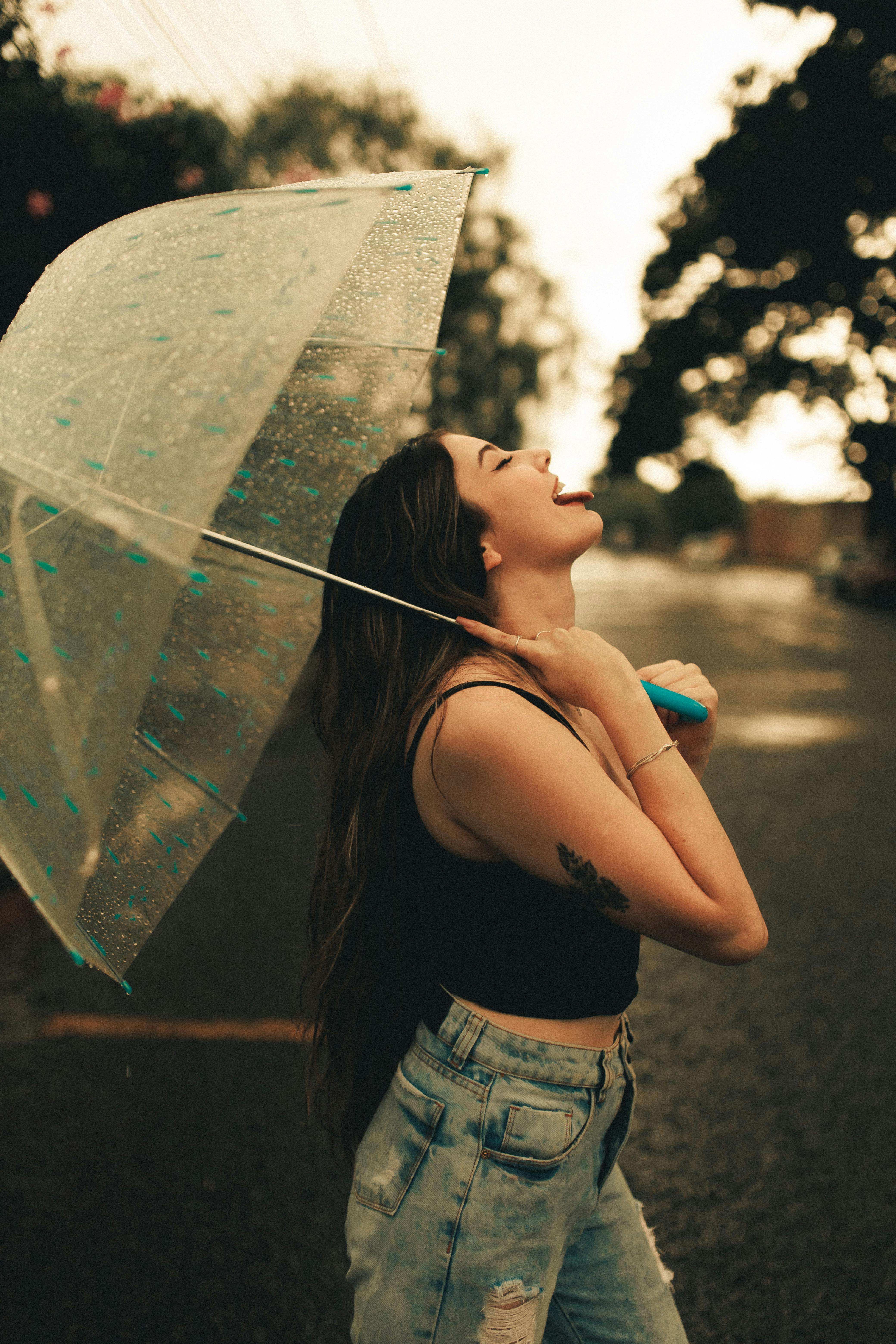 While playing in the rain, a teenage girl poses with an umbrella in front  of her face Stock Photo - Alamy