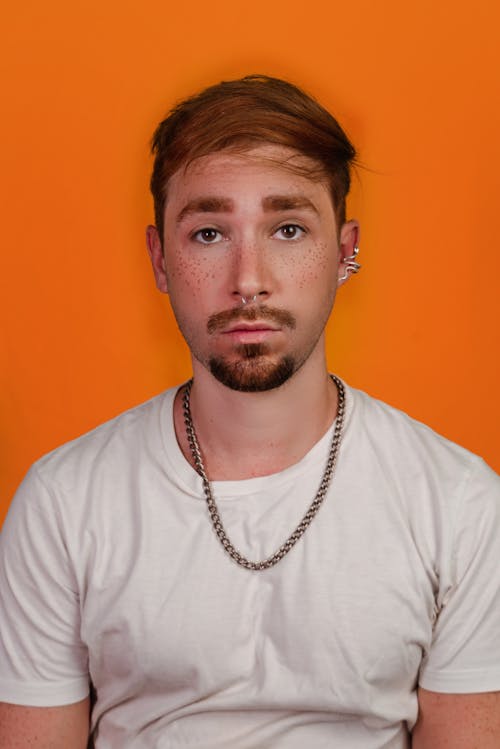 Studio Portrait of a Young Man with Mustache and Stubble, Wearing a White T-shirt and a Chain 