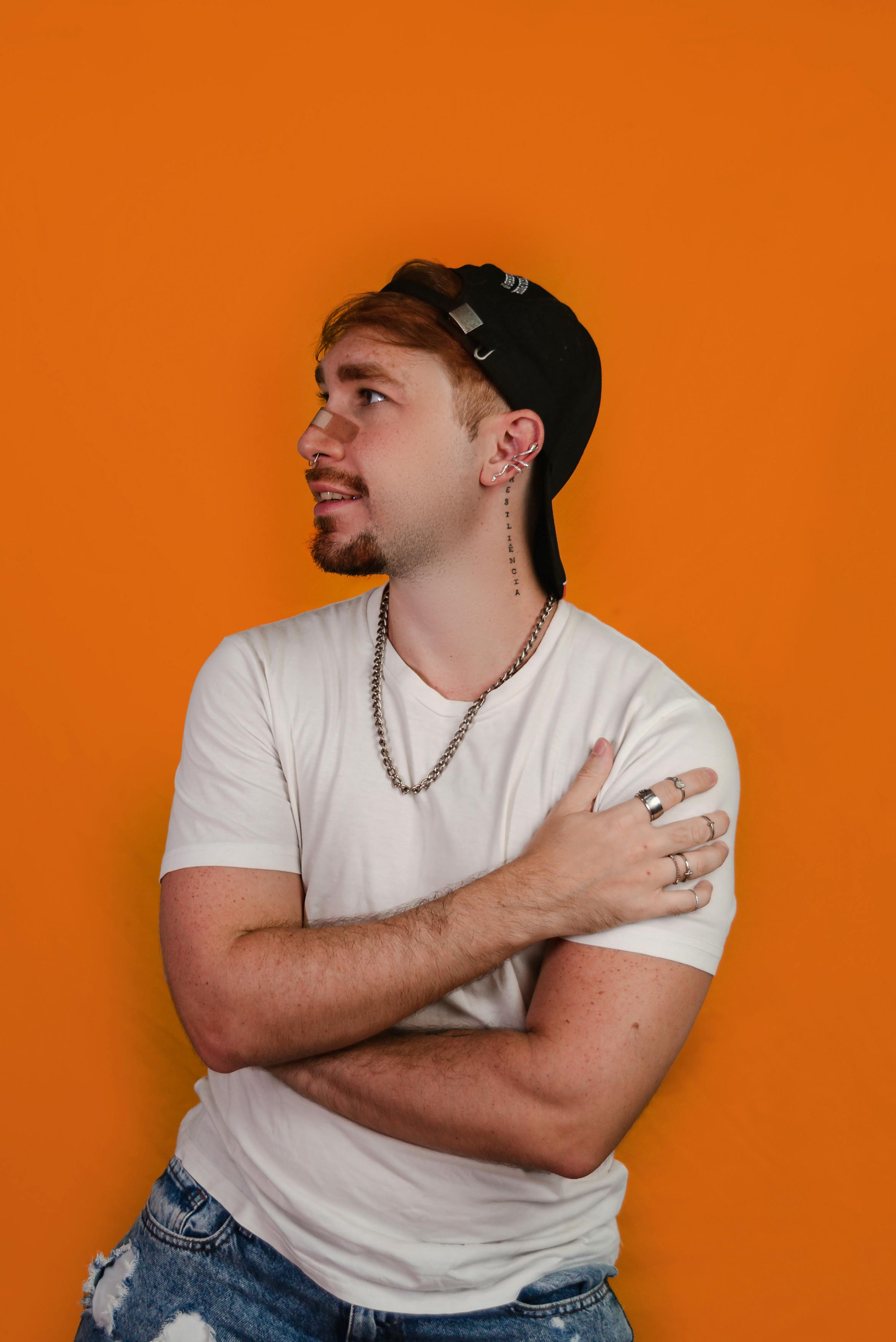 Portrait of a young man in casual attire against an orange backdrop. Studio shot.