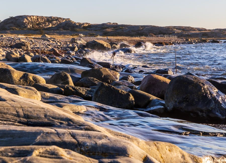 Dramatic rocky coast of Havstenssund, Sweden, with waves crashing during sunset.