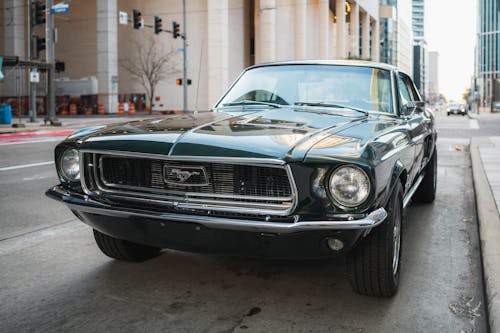 A Green Ford Mustang from the 1960s Parked on a Side of a Street 