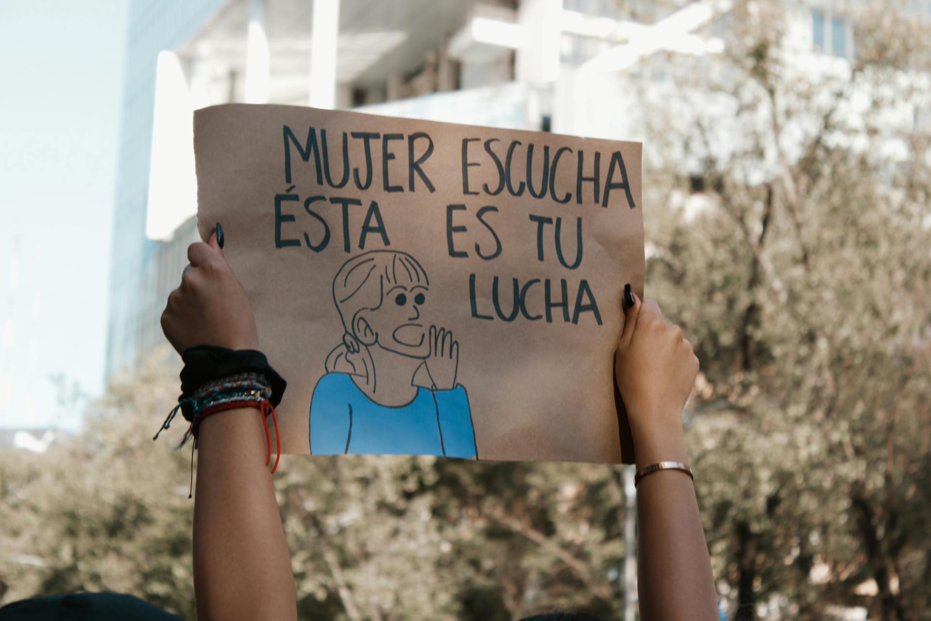 Hands Holding Banner in Spanish