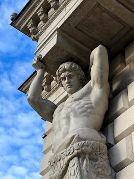 Close-up of a marble Atlas statue in St. Petersburg's classic architecture against a clear blue sky.